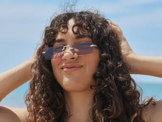 Person outdoors holding their hair back with sunglasses on their face