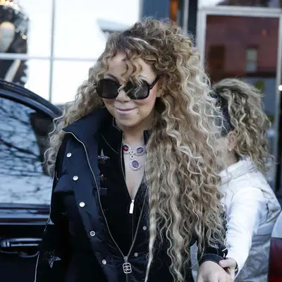 Mariah Carey with long curly blonde hair outside a car