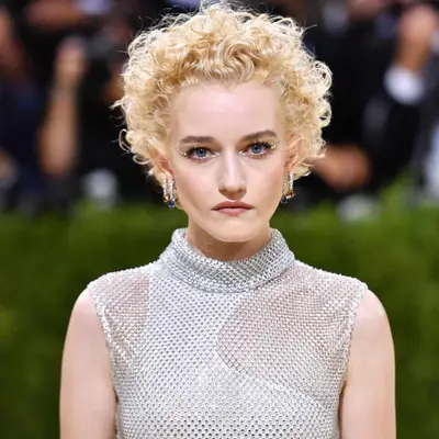 Julia Garner with short curly blonde hair on the red carpet