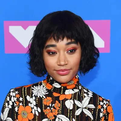 Amandla Stenberg wears a layered curly wedge haircut with bangs
