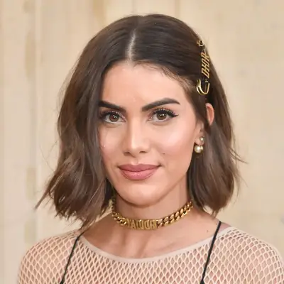 Camila Coelho wears a wedge lob haircut with a Dior clip