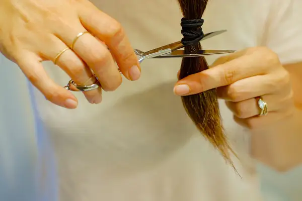 woman cutting her ponytail with shears