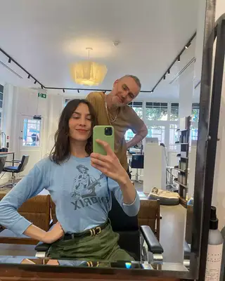 Alexa Chung taking a selfie in a blue shirt