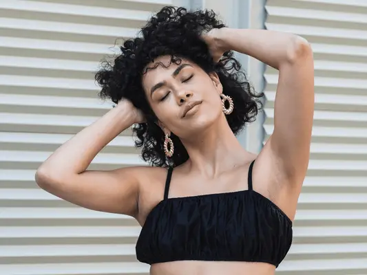 A woman with curly hair running her hands through it