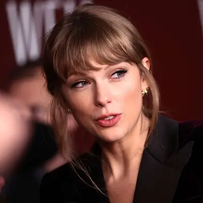 Taylor Swift wears a low updo hairstyle with bangs and wispy face-framing layers