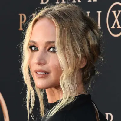 Jennifer Lawrence wears a low bun hairstyle with wavy face-framing pieces and shimmery eyeshadow