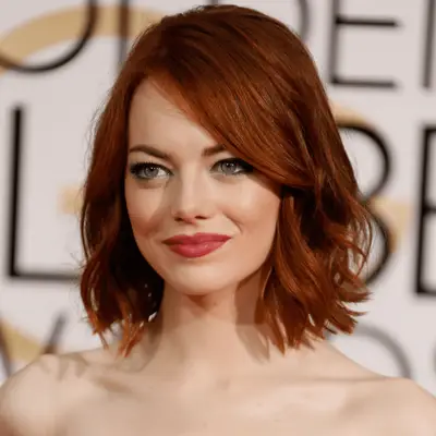 Anitta wears her highlighted copper balayage with visible dark roots in a center part with touchable waves and a black velvet deep v-neck dress