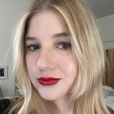 MYM Beauty editor Bella Cacciatore with soft blonde hair and a radiant makeup look with red lipstick
