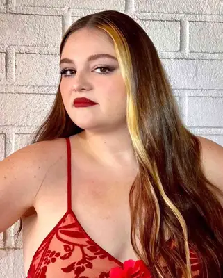 Actor Meg Stalter with long brown hair and a blonde money piece highlight