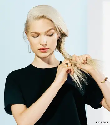 woman braiding the bottom of her blonde hair into a fishtail braid