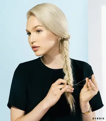 woman with blonde hair securing her fishtail braid with a clear elastic
