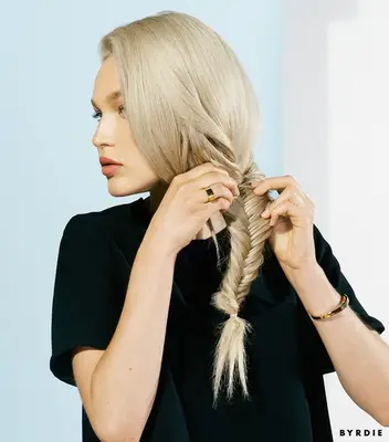woman with blonde hair teasing her fishtail braid with her hands
