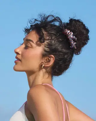 Person in profile with hair in a bun wearing earrings and a top