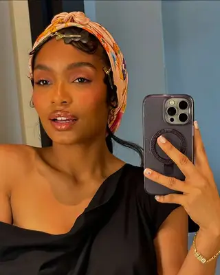 Yara Shahidi in a selfie with a phone, wearing a headscarf and black top, indoors