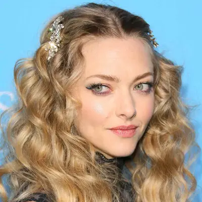 Amanda Seyfried wears big bouncy curls in a center part with two bedazzled barrettes