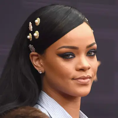 Rhianna wears a swide swept hairstyle with bedazzled buttons on each side