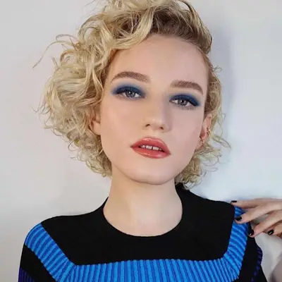 Julia Garner with a tousled, curly side part bob