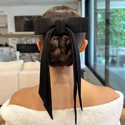 Olivia Culpo viewed from behind, her hair in a sleek braided bun with a bow
