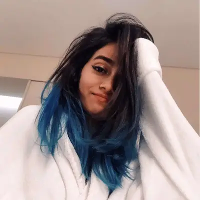 Woman with straight blue ombre hairstyle with natural dark roots