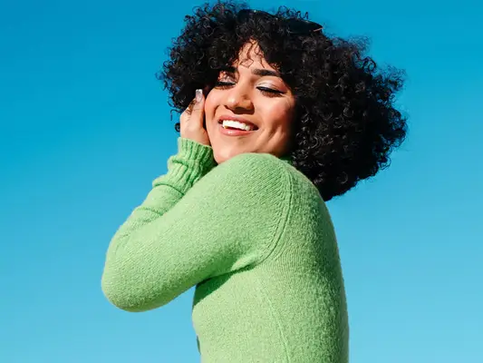 Portrait of a beautiful latina trans woman smiling with confidence with the blue sky behind
