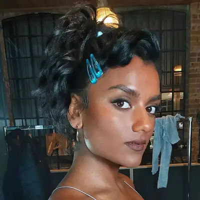Simone Ashley with a 2000s-inspired pouf updo, secured with two cobalt blue clips.