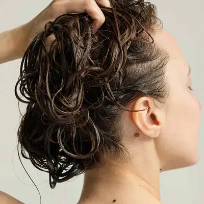 Woman holds up her wet hair in a close up 