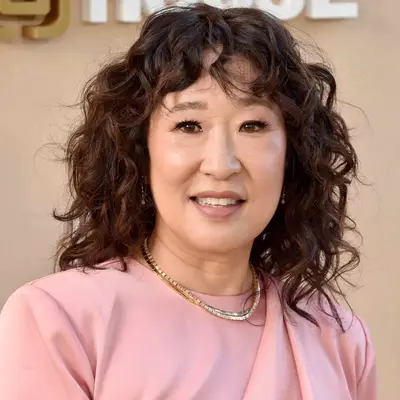 Sandra Oh wears a curly medium-length hairstyle with face-framing bangs