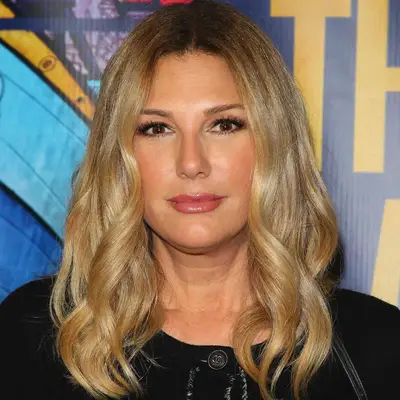Daisy Fuentes wears a golden blonde medium-length hairstyle with loose curls