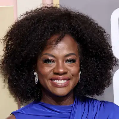 Viola Davis wears a medium-length naturally curly hairstyle with layers and bangs