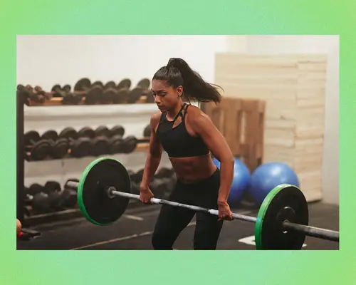 Woman weight lifting a barbell in a gym.