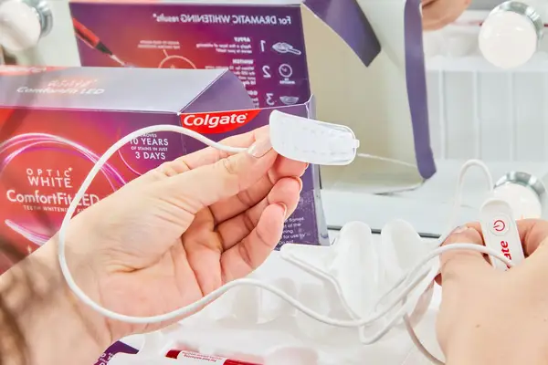 Hands holding the Colgate ComfortFit LED Teeth Whitening Kit
