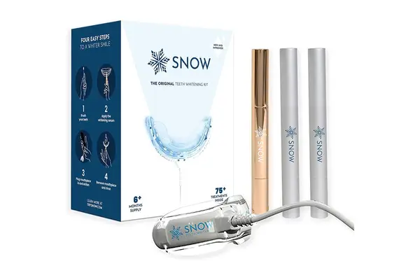 Person in baseball cap with facial hair using a red teeth whitening device