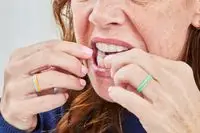 A person placing one of the Crest 3DWhitestrips 1 Hour Express