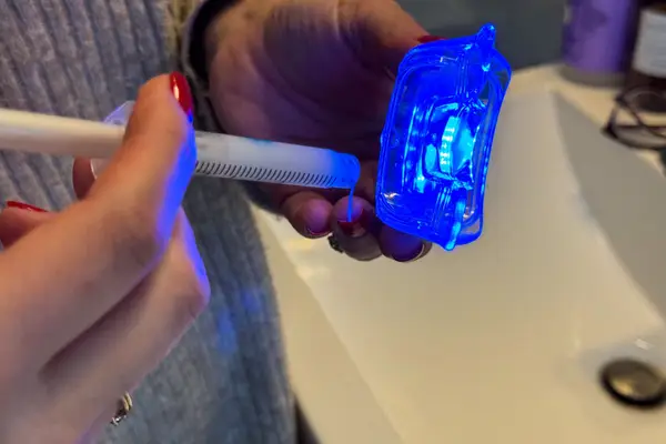 A person uses the HeySmile Teeth Whitening Kit LED light