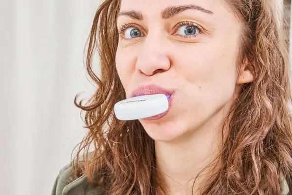 Hands opening Crest Whitening Emulsions Leave-on Teeth Whitening Gel Kit on table near laptop