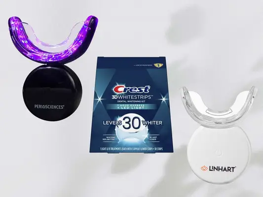 Three LED Teeth Whitening Kits on a grey background, including Periosciences, Crest, and Linhart