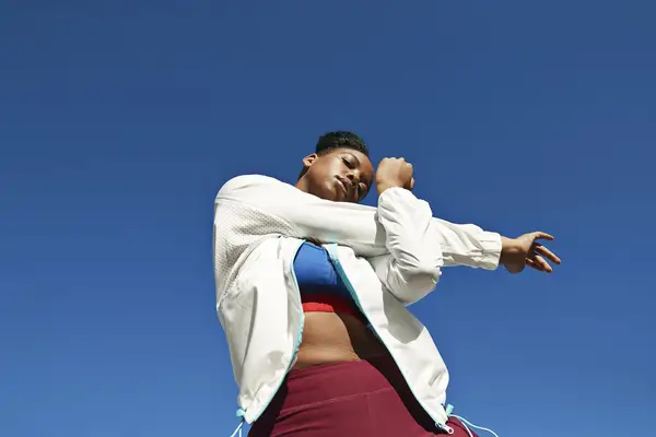 woman in white jacket stretching arms before a workout