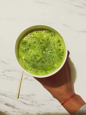 hand holding a paper cup of matcha green tea