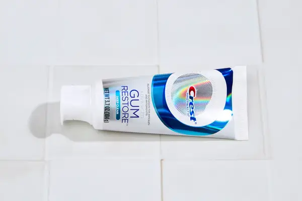 A tube of Crest Pro-Health Advanced Gum Restore Whitening Toothpaste on white tile