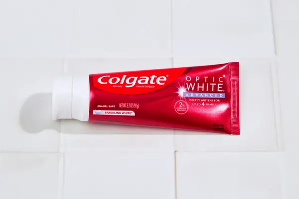 a tube of Colgate optic white toothpaste on a bathroom counter