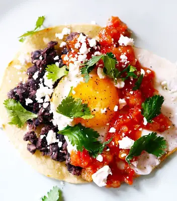 Tortilla with an egg, beans, cheese, tomatoes, and cilantro