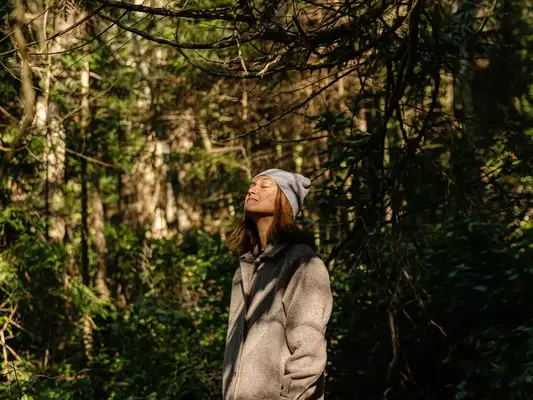 Woman hiking and taking a moment to relax in forest.