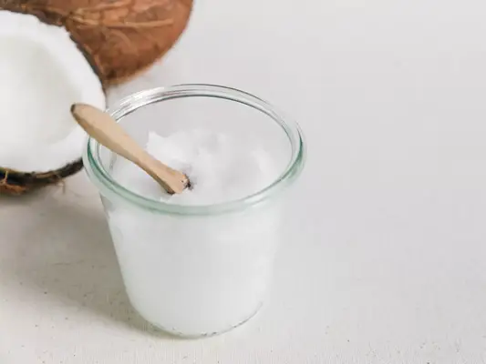 Close up of a coconut and a jar with solid coconut oil