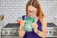 Woman smells package of Dr. Mercola Fermented Greens Powder