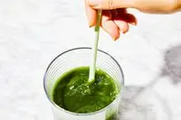 Person stirring a drink using the Ora Organic Easy Being Green Superfood Greens Powder