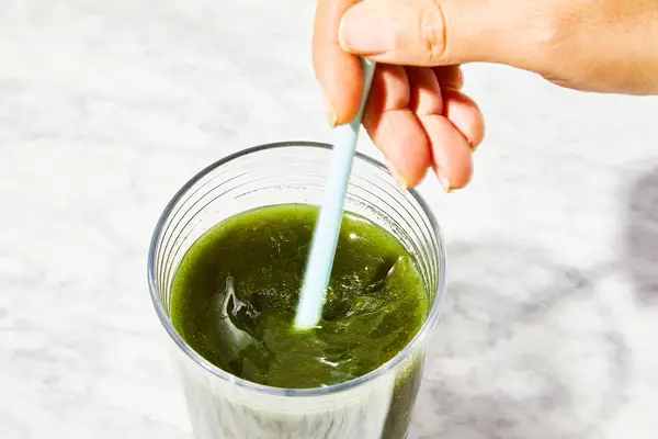 Close-up of a hand stirring Primal Harvest Primal Greens