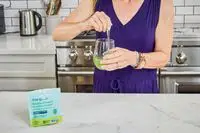 Woman stirs True Grace Superfood Powder Broccoli Microgreens into a glass of water