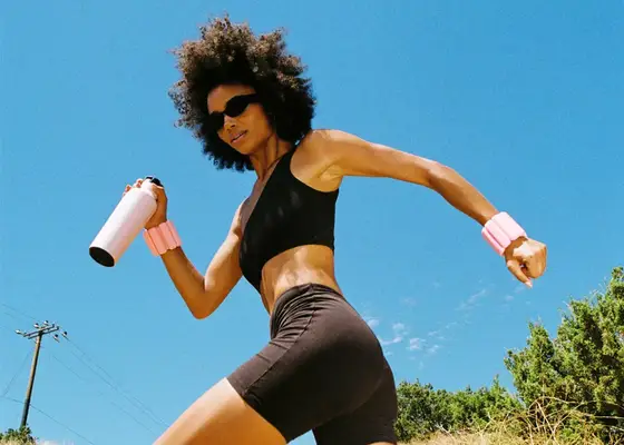 Woman walking in a black workout set wearing wrist weights