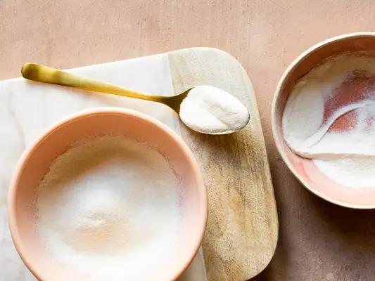 Composed image of two bowls and a spoon with collagen powder