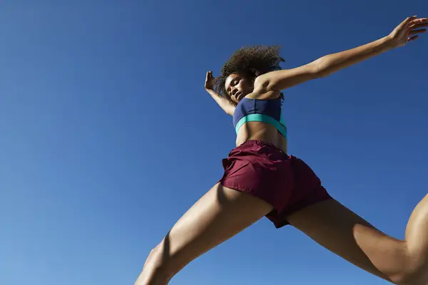 Young woman exercising against clear sky